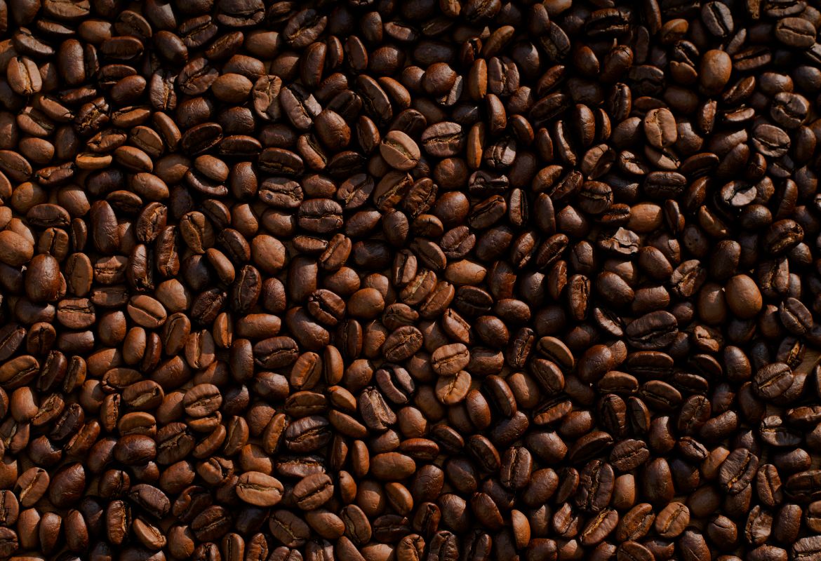 Aromatische, dunkel geröstete Kaffeebohnen in Nahaufnahme, dicht aneinandergereiht für frische Kaffeezubereitung.