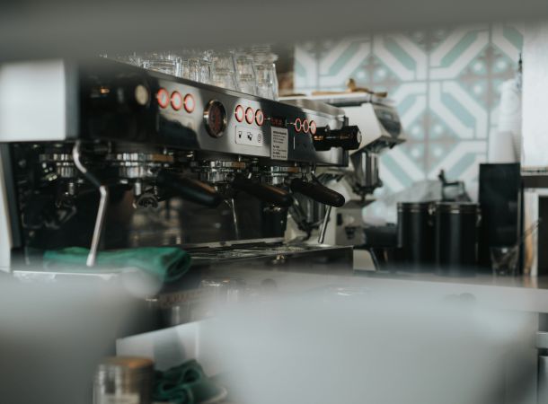 Gastronomie-Siebträgermaschine mit mehreren Brühgruppen und Barista-Zubehör in einer Café-Theke.
