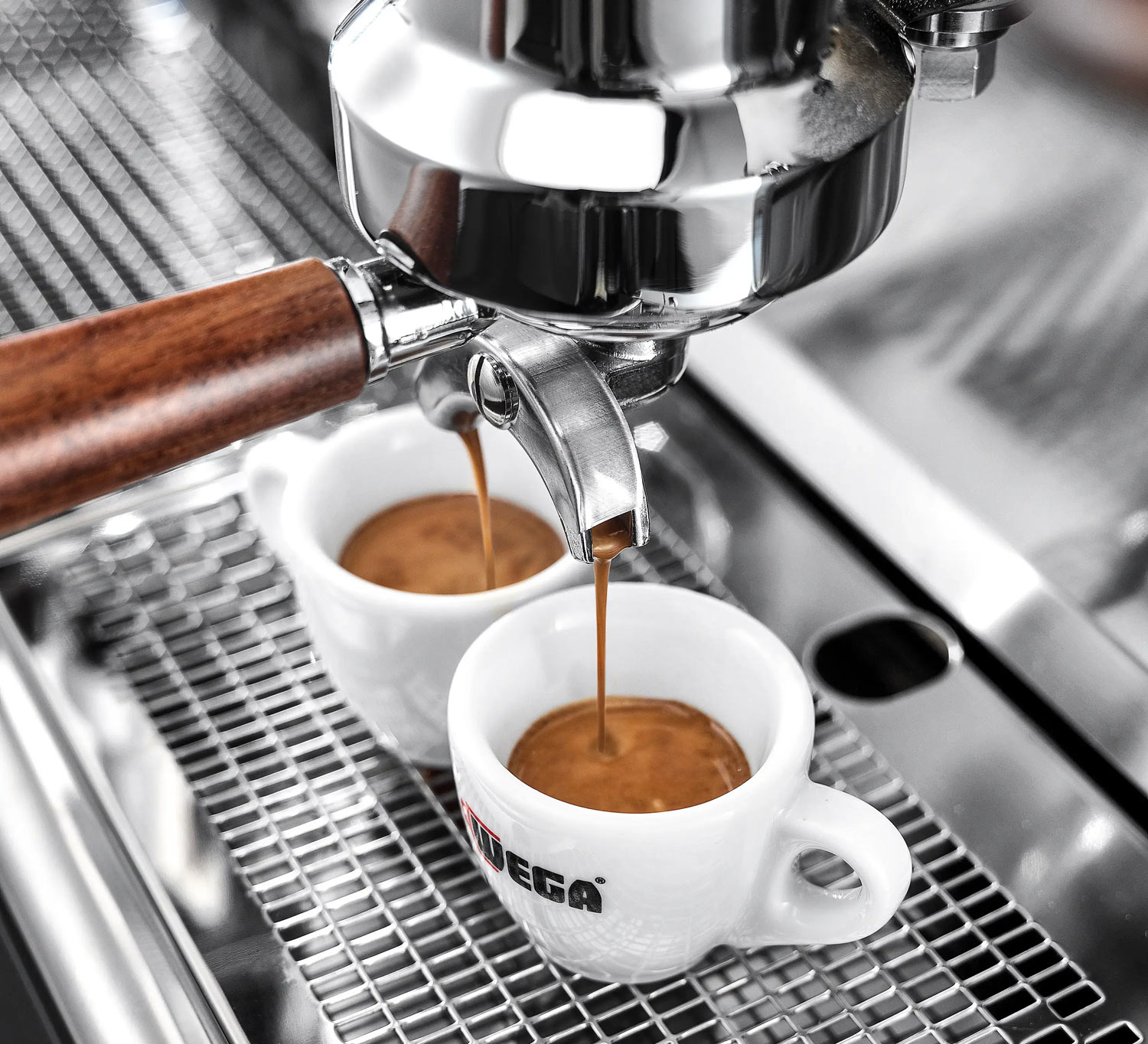 Frisch gebrühter Espresso läuft aus der Siebträgermaschine in zwei kleine Tassen.