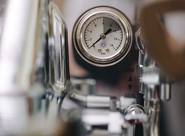 Nahaufnahme eines Manometers und Bedienelementen an einer Siebträgermaschine aus Edelstahl.