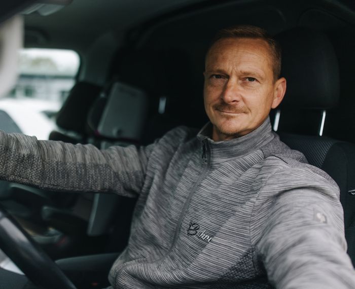 Servicetechniker von Bahro Kaffeemaschinen sitzt im Einsatzfahrzeug und blickt in die Kamera.