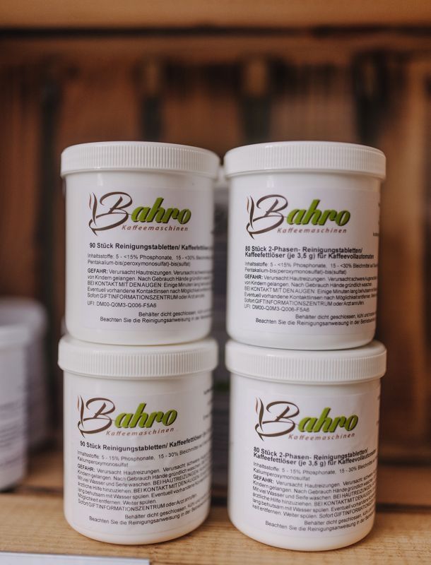 Mehrere Dosen Bahro Reinigungstabletten für Kaffeemaschinen ordentlich im Regal gestapelt.