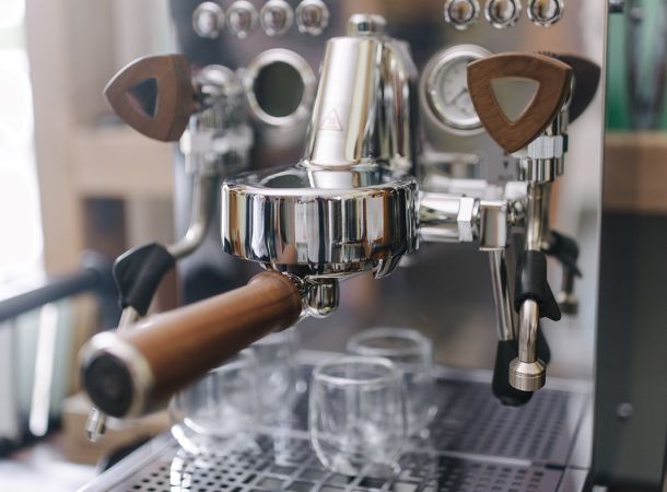 Graef Siebträgermaschine aus Edelstahl mit Holzgriffen und eingesetzten Espressogläsern auf der Abtropffläche.