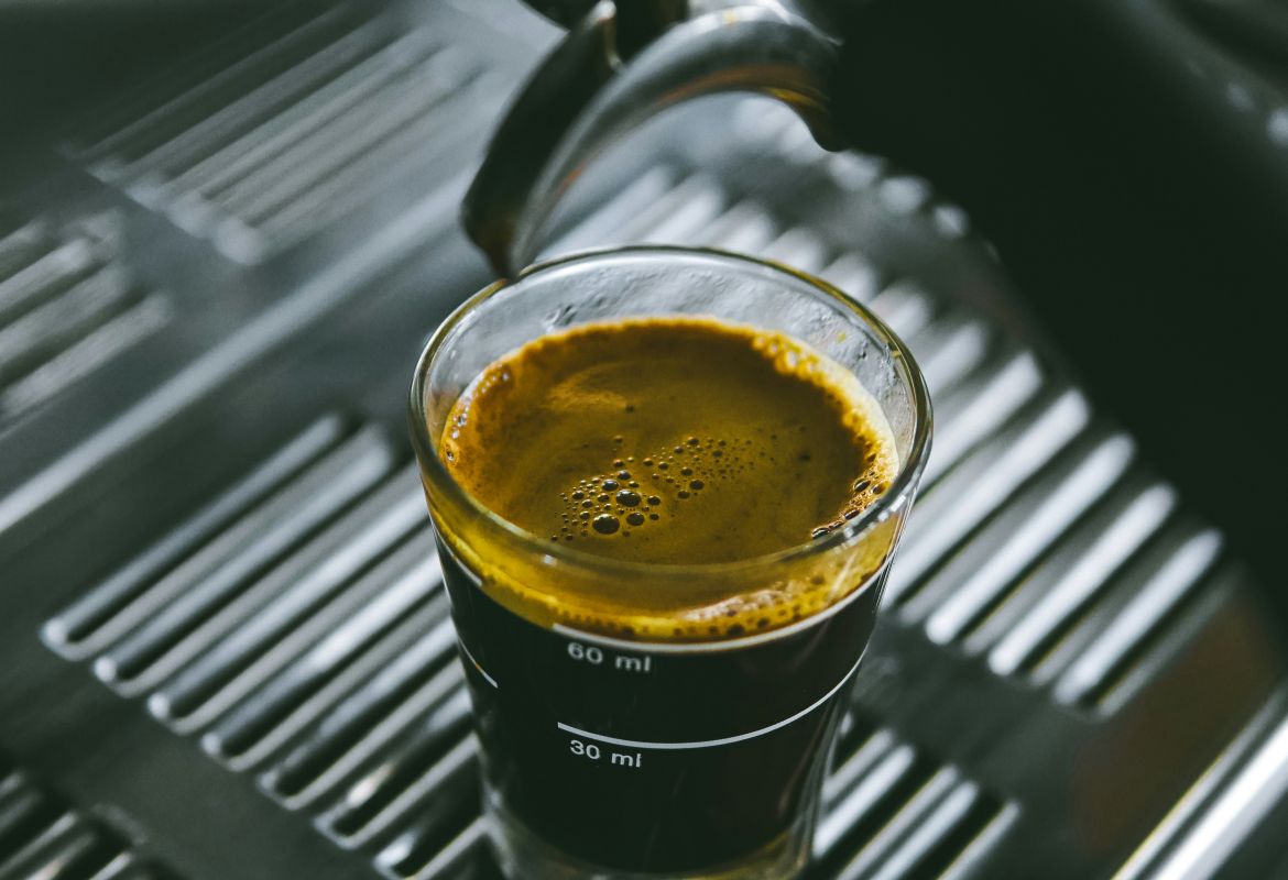 Frisch aufgebrühter Espresso in einem Messglas unter dem Siebträger einer Espressomaschine.