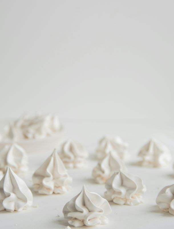 Mehrere kleine weiße Sahne-Häubchen auf heller Oberfläche, minimalistisch arrangiert.