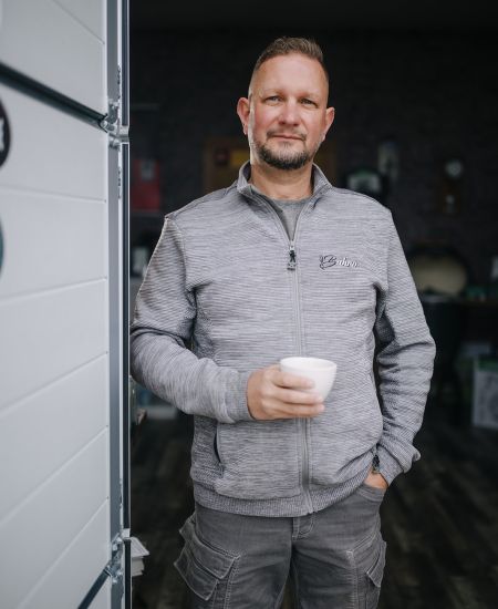 Mitarbeiter von Bahro Kaffeemaschinen mit Kaffeetasse vor der Werkstatt stehend.