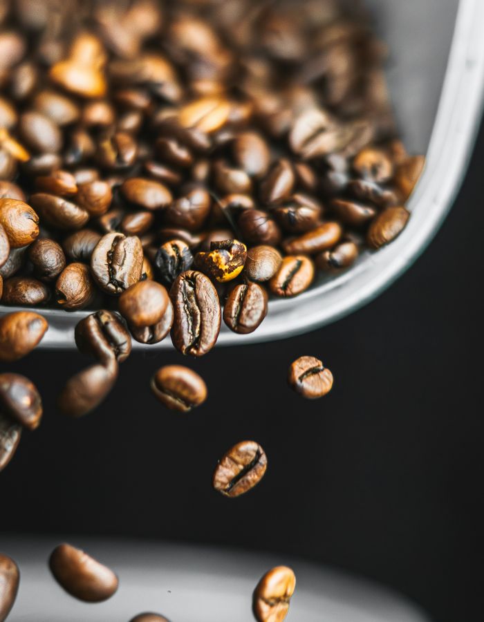 Nahaufnahme frisch gerösteter Kaffeebohnen, die aus einem Behälter fallen.